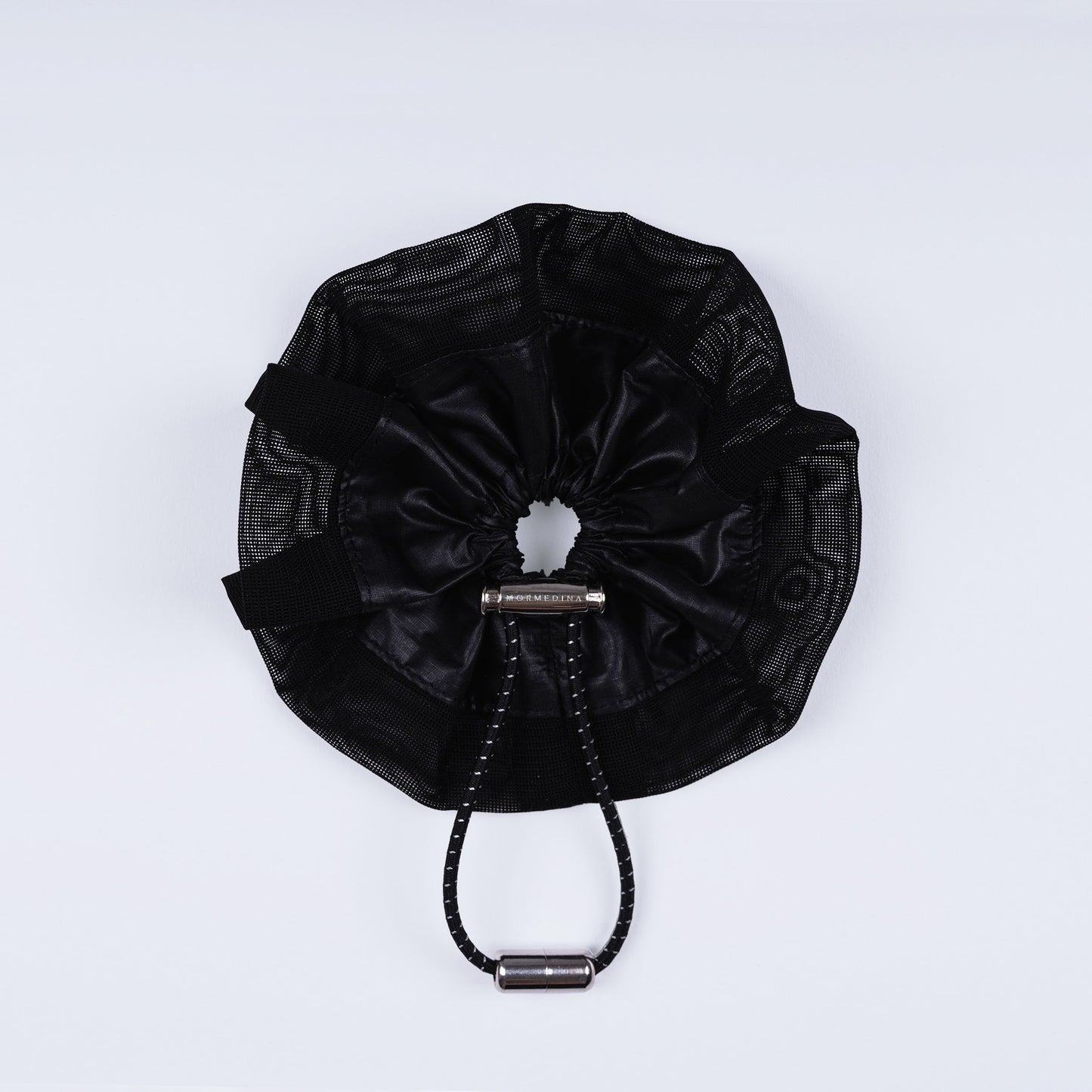 A black ripstop nylon and mesh adjustable scrunchie, displayed closed on a white background to show its sleek fastener design.