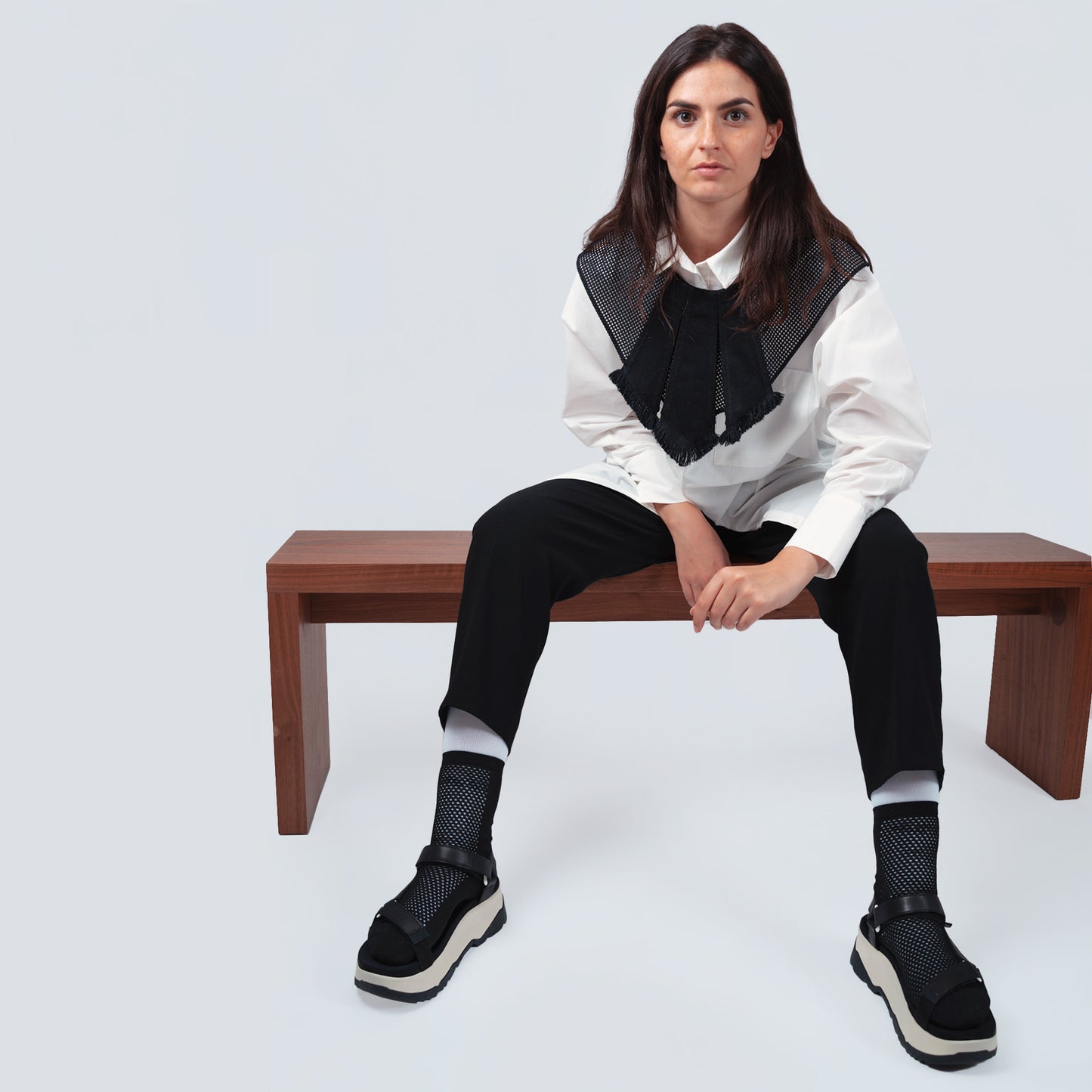 Model wearing the black collar over a buttoned poplin shirt