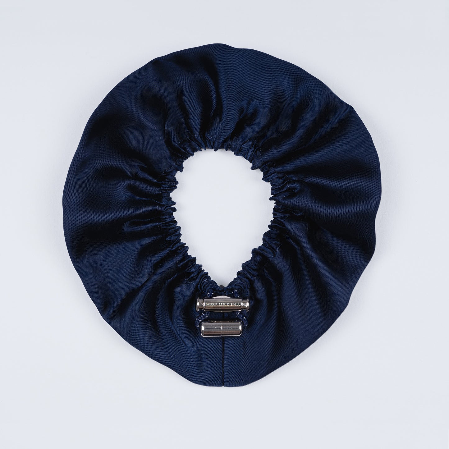 Night blue silk scrunchie opened fully, revealing flexible elastic and luxurious silk material.