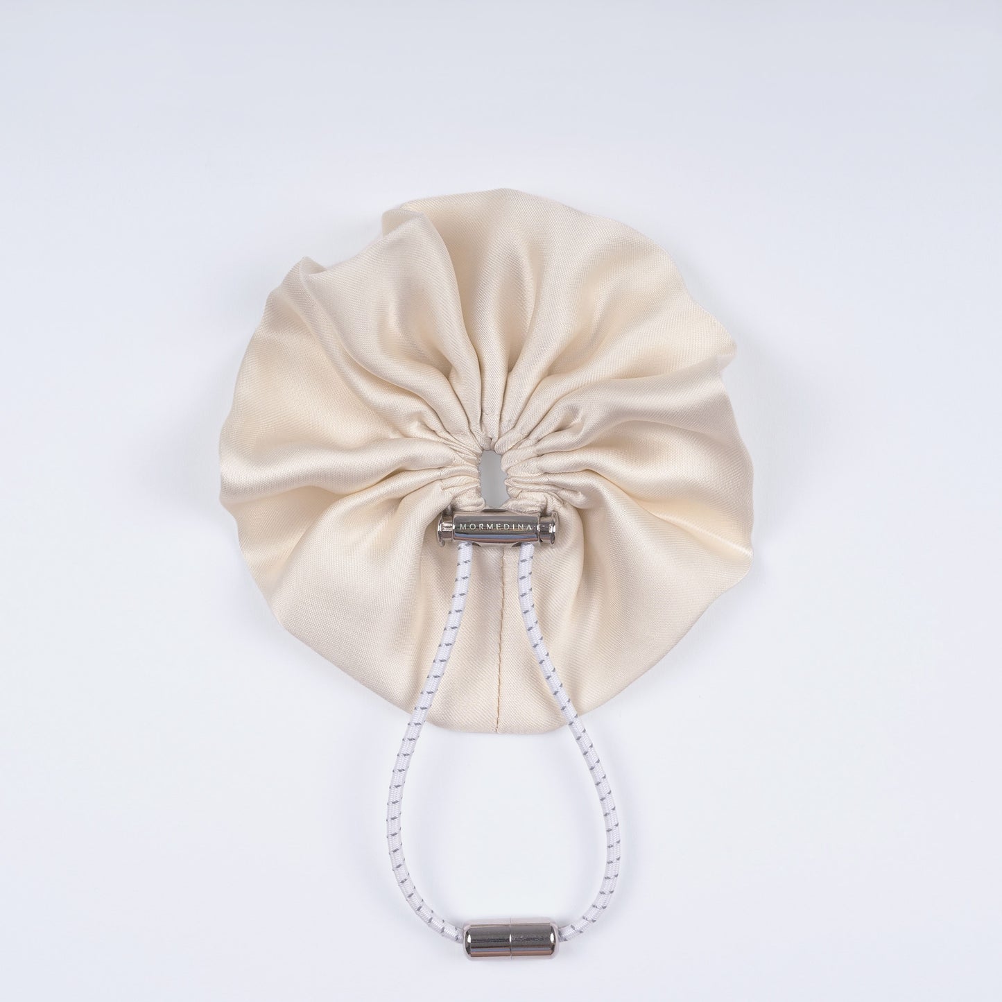 Ivory silk scrunchie displayed closed on a white background, showing its smooth texture and unique fastener.