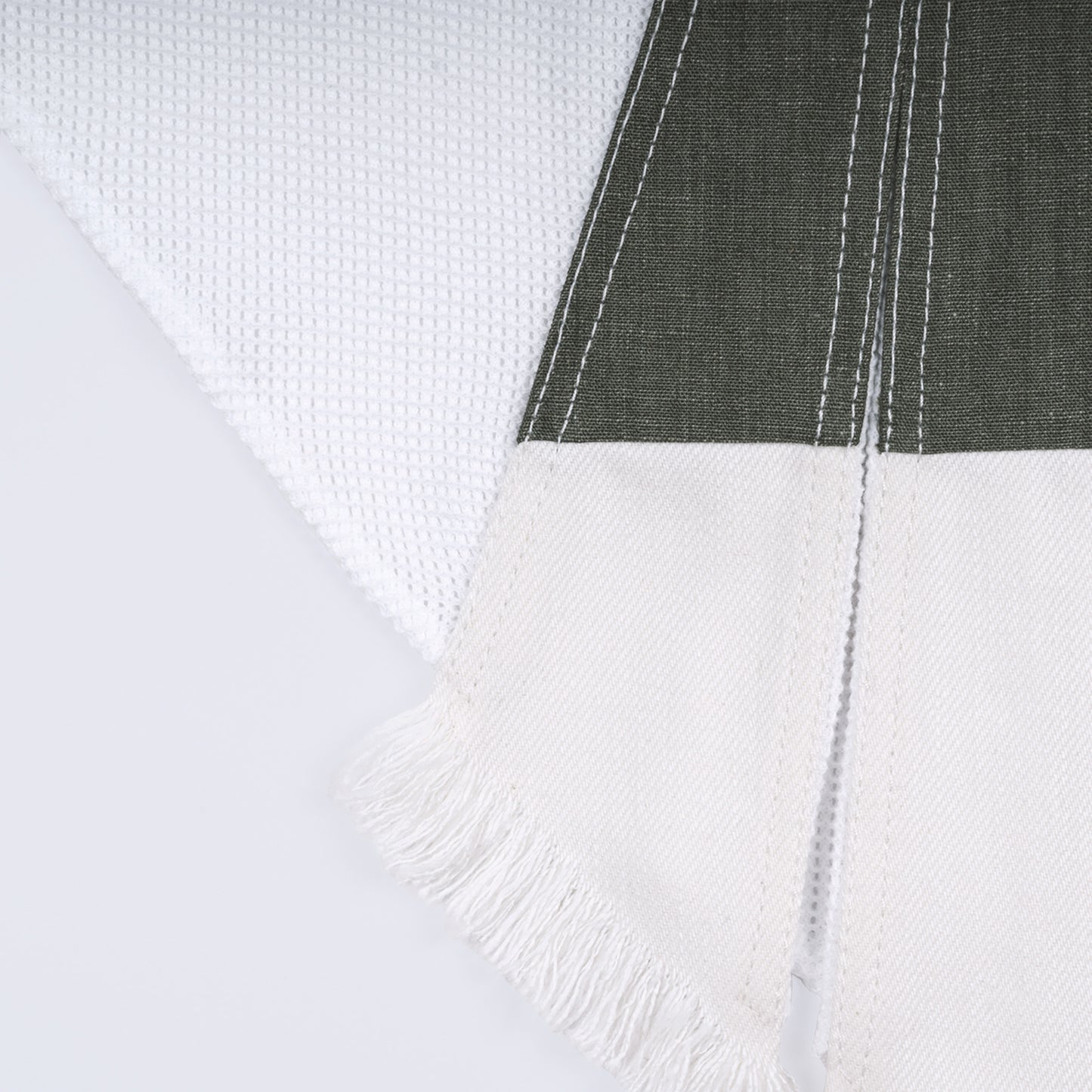 Close-up of olive green canvas, white denim, and cotton mesh fabrics