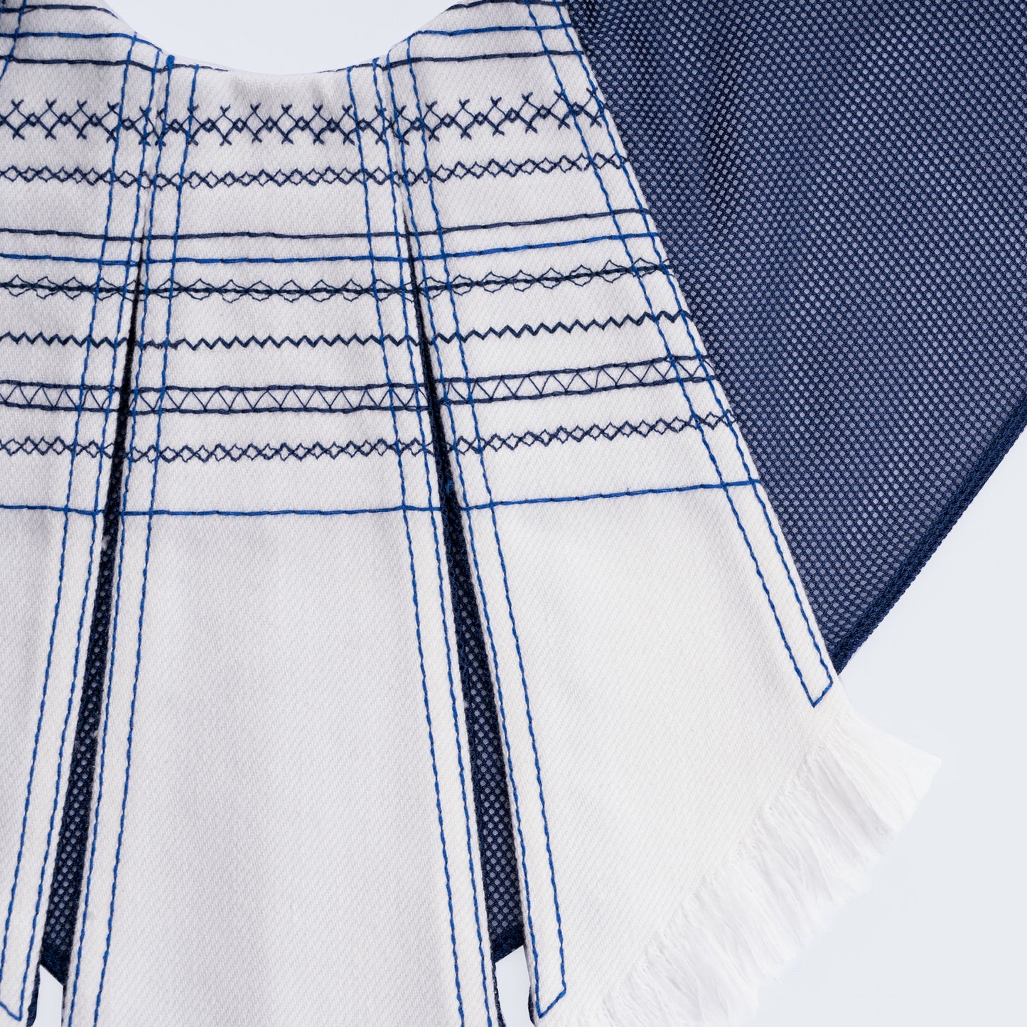 Close-up of white embroidered denim and blue mesh fabric