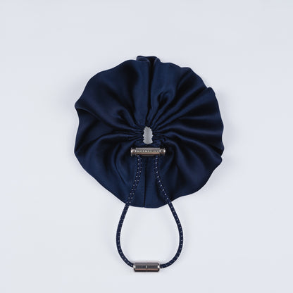 Night blue silk scrunchie displayed closed on a white background, highlighting its smooth texture and unique fastener.