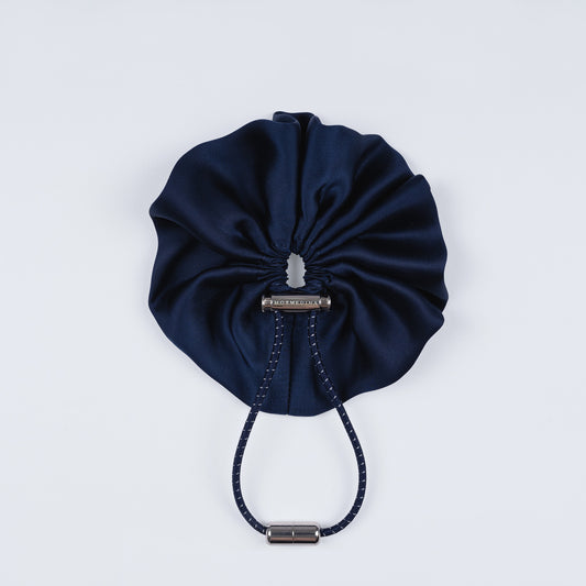 Night blue silk scrunchie displayed closed on a white background, highlighting its smooth texture and unique fastener.