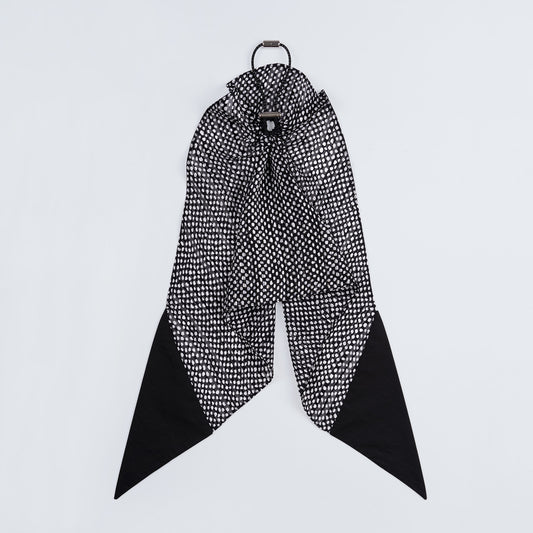 Black and white dotted silk scrunchie displayed closed on a white background, highlighting its unique fastener.