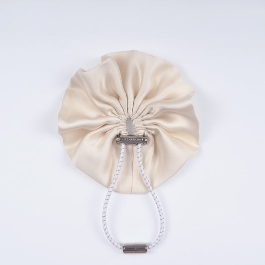 Ivory silk scrunchie displayed closed on a white background, showing its smooth texture and unique fastener.