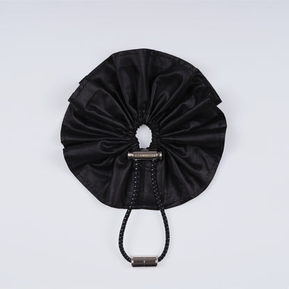 A black ripstop nylon scrunchie, displayed closed on a white background to highlight its sleek fastener.
