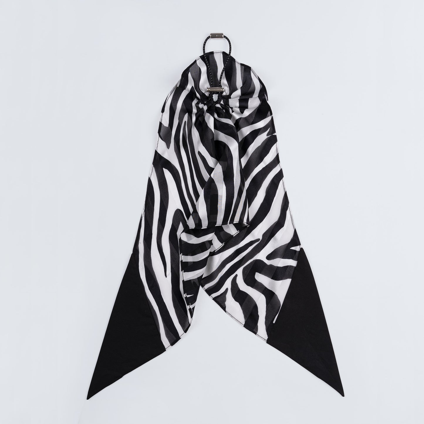 Black and white zebra print silk scrunchie displayed closed on a white background, highlighting the unique fastener and smooth texture.