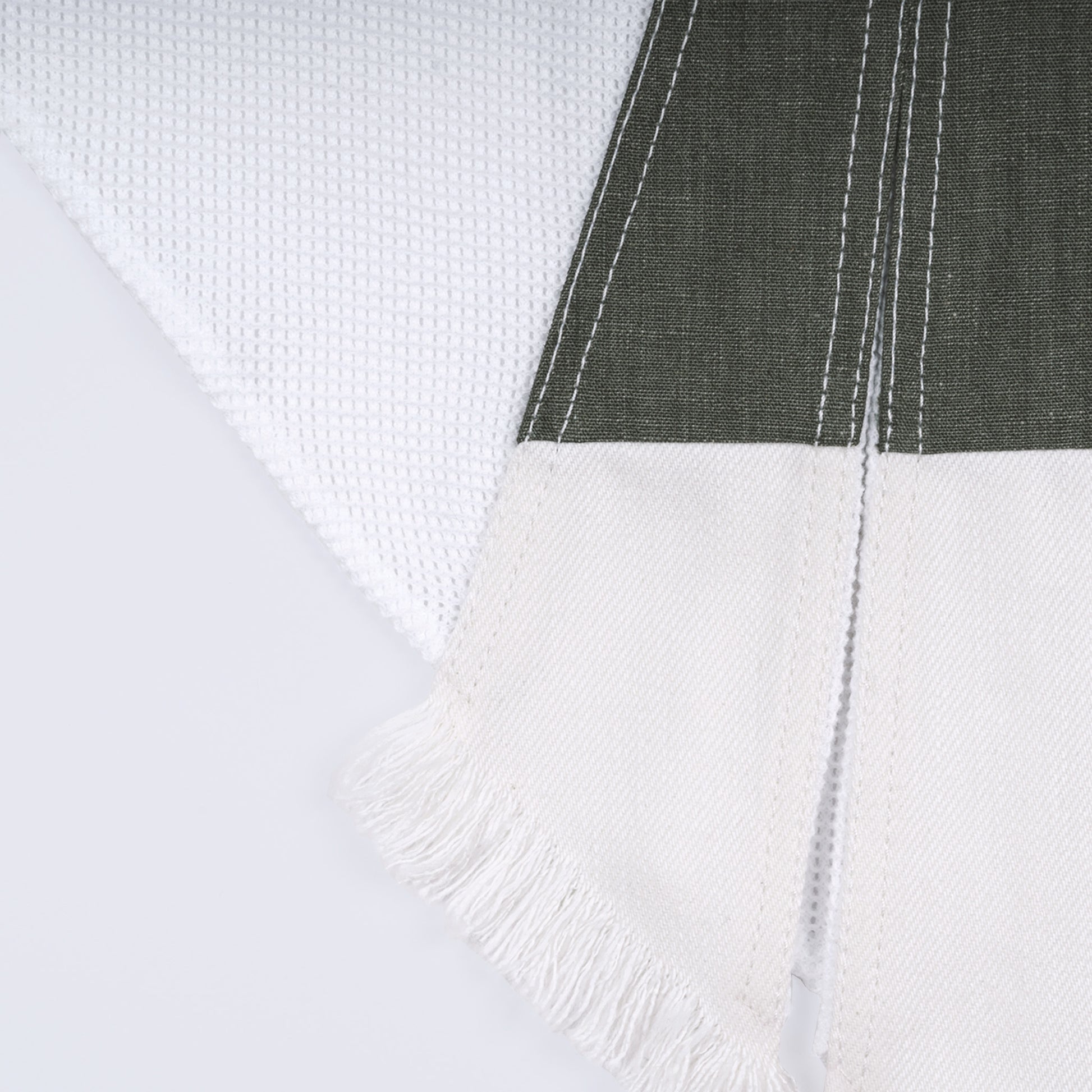 Close-up of olive green canvas, white denim, and cotton mesh fabrics